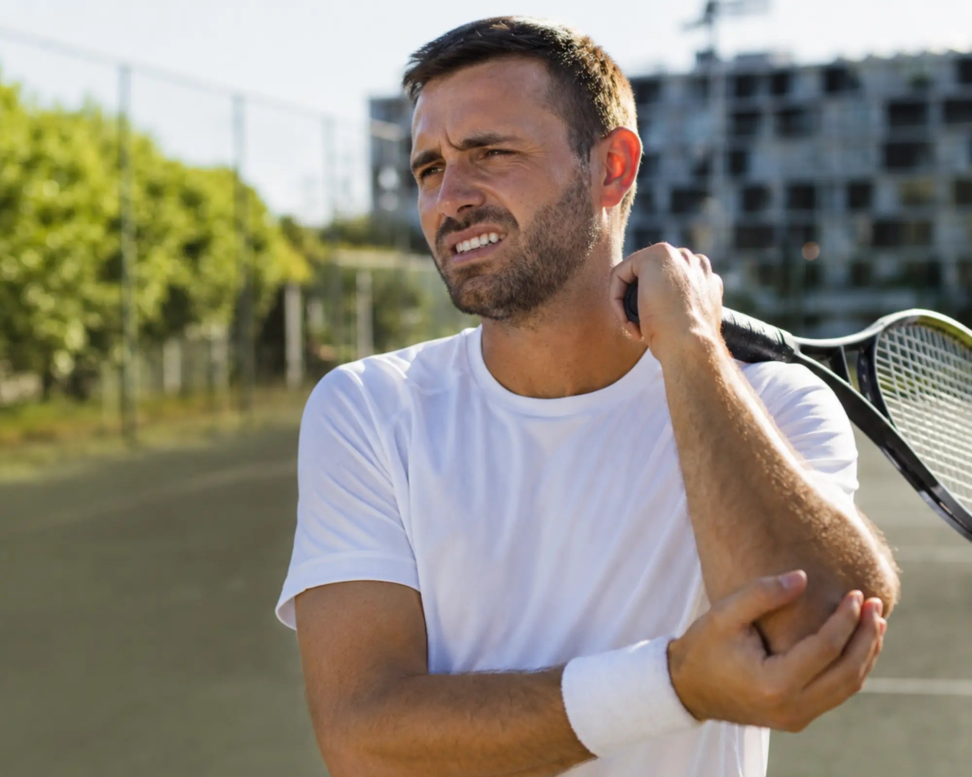 Man holding a tennis racket on a tennis court with an arm injury